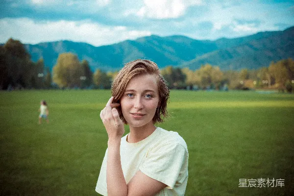 高清摄影 一个女孩在田野里，背景是山脉。