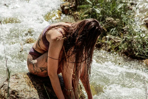 高清摄影 一个穿着泳衣的女人蹲在一条小溪旁