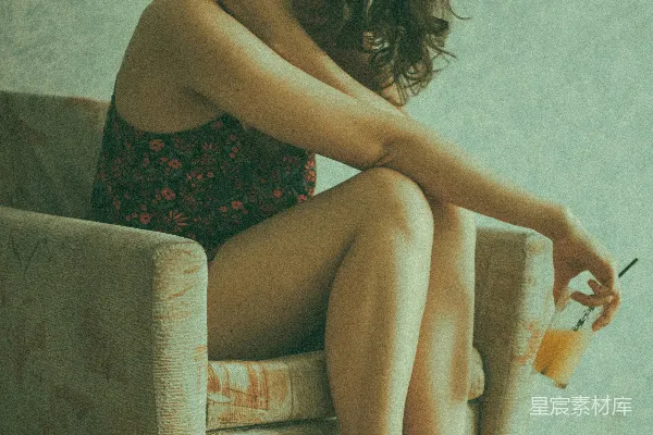 高清摄影 穿着黑色花卉图案吊带连衣裙的女人坐在棕色沙发上。