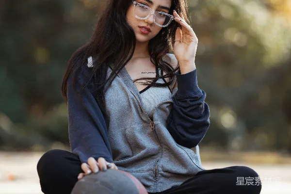 高清摄影 年轻的女孩坐在那里，手里拿着篮球，戴着眼镜。