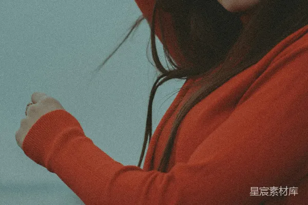 高清摄影 一个穿着红色连帽衫的女人站在海边。