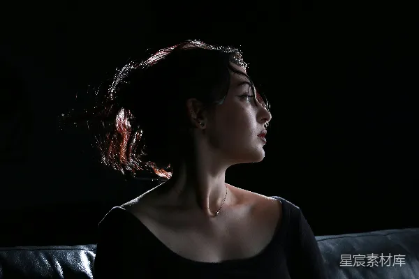 高清摄影 一个女人在黑暗中坐在沙发上。