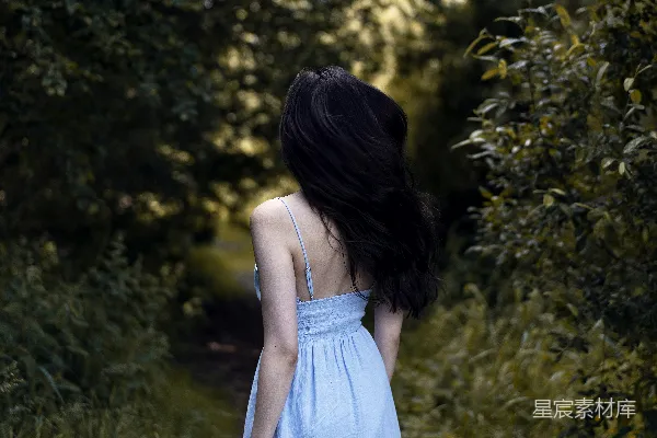 高清摄影 一位穿着蓝色连衣裙的女人沿着小路走着