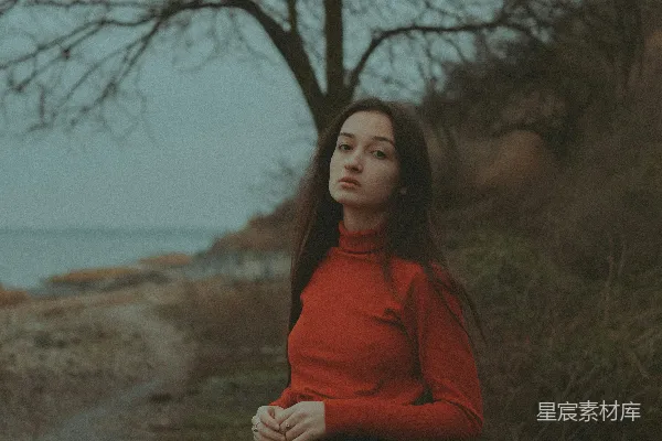 高清摄影 一个穿着红色上衣的女人站在一棵树旁边。