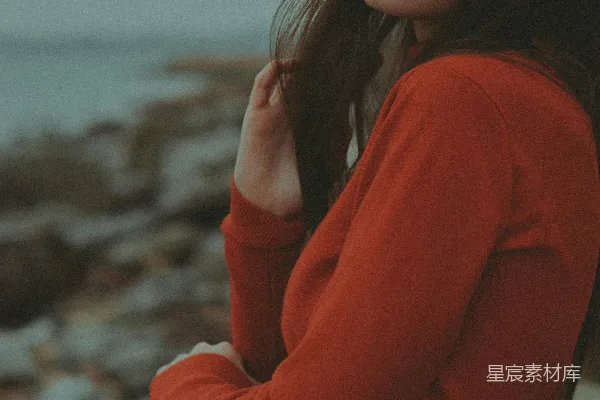 高清摄影 一个穿着红色毛衣的女人站在岩石海滩上