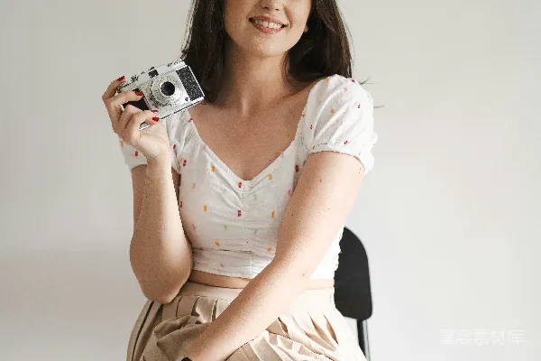 高清摄影 一个女人坐在椅子上拿着相机。
