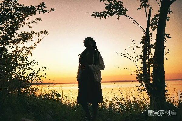 高清摄影 一位女士站在湖边，夕阳西下。