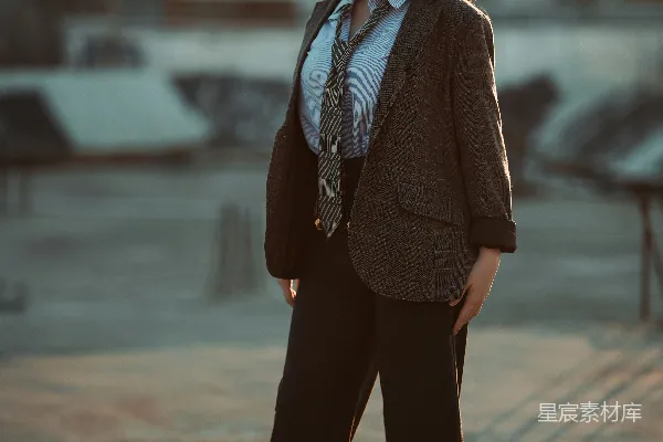 高清摄影 一个穿着西装的女人站在户外，夕阳西下。