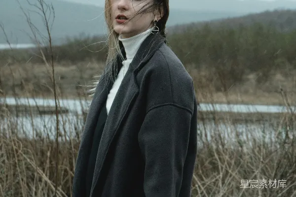 高清摄影 穿着黑色夹克的女人站在白天湖边的草地上。