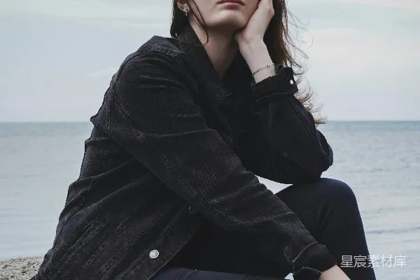 高清摄影 穿着黑色外套的女人坐在海边的岩石上，白天。