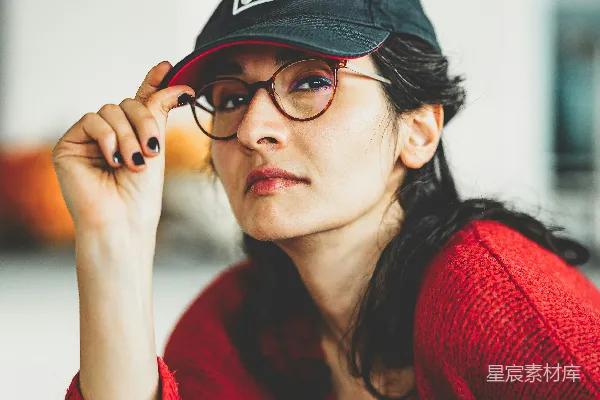 高清摄影 一个戴着帽子和眼镜的女人坐在桌子旁。