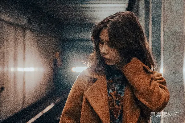 高清摄影 一个女人站在地铁站里，手放在头上。