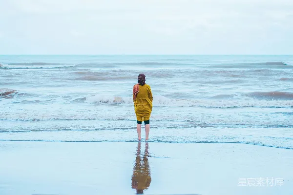 高清摄影 穿着黄色连帽衫的男子在白天的海滩上行走。