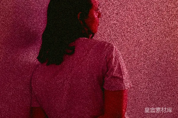 高清摄影 一个女人坐在粉红色墙前的凳子上。
