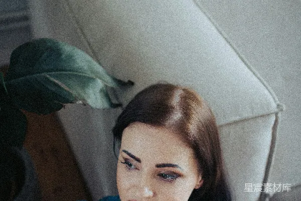 高清摄影 一个女人坐在沙发上，手托着下巴。