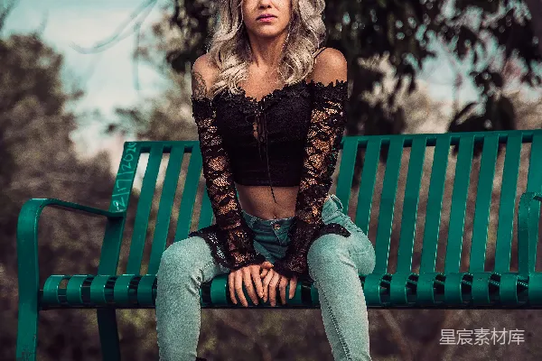 高清摄影 一个女人坐在绿色的长椅上。
