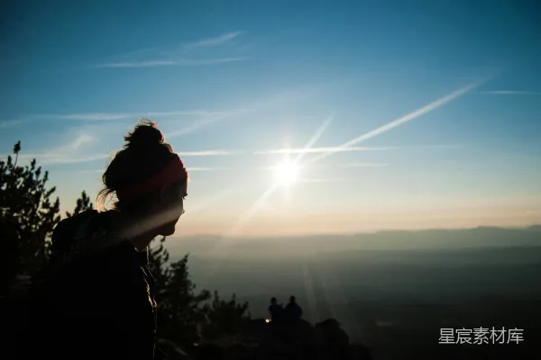 高清摄影 一位女子站在山顶上，天空湛蓝。