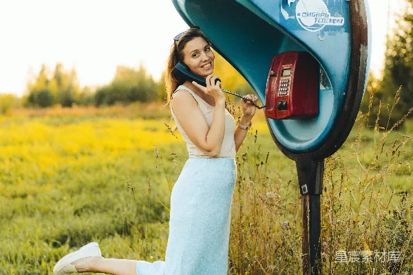 高清摄影 一个穿着蓝色连衣裙的女人正在打电话。