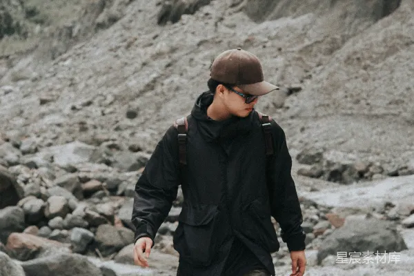 高清摄影 一个戴着帽子的男人在岩石海滩上行走