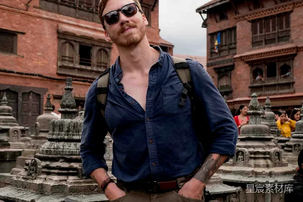 高清摄影 一个背着背包的男人站在建筑物前。