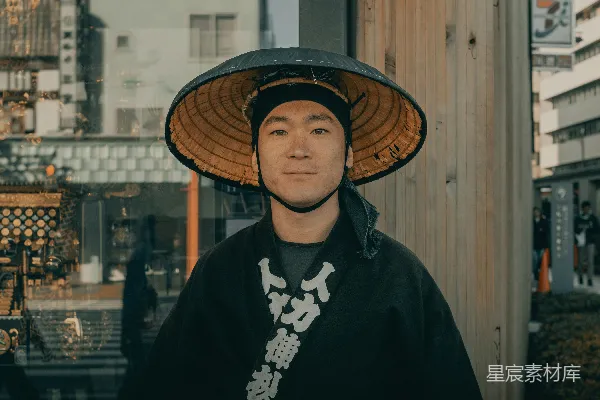 高清摄影 穿着黑色外套的女人戴着棕色编织的帽子，站在白天的棕色木墙旁边。