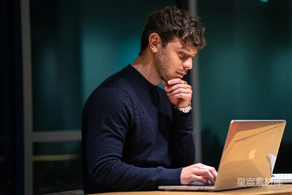 高清摄影 穿黑色长袖衬衫的男人坐在MacBook前。