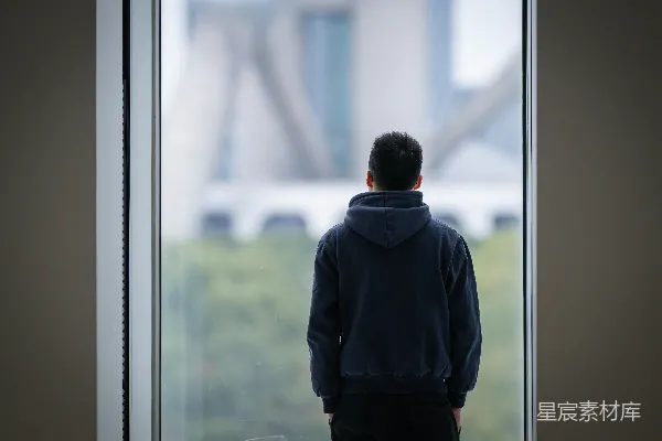 高清摄影 一个男人站在窗前，向窗外看去。