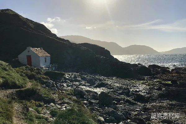 高清摄影 一座小白屋坐落在水边岩石山坡上。