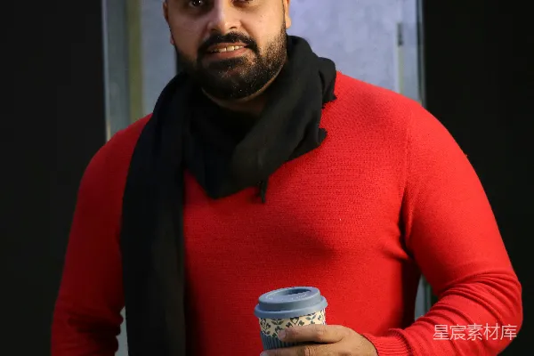 高清摄影 穿红色毛衣的男人拿着一个白蓝陶瓷杯子。