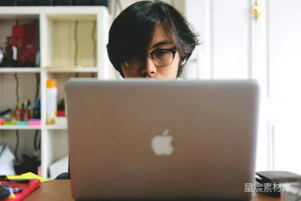高清摄影 戴眼镜的男人在房间里用银色的MacBook靠近木制的壁柜。