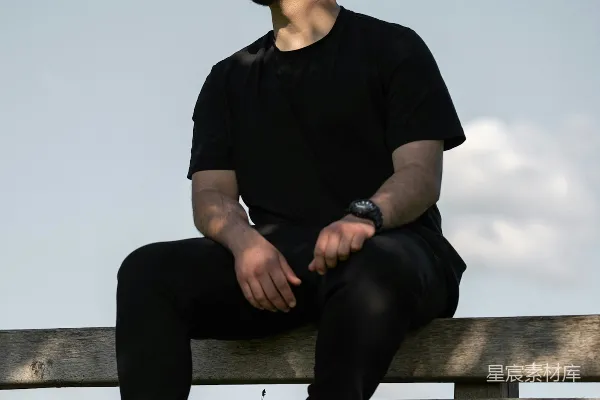 高清摄影 一个男人坐在一个木制的长凳上。