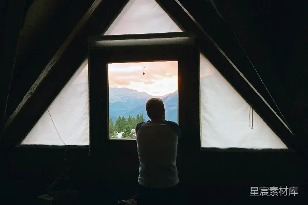 高清摄影 一个人站在窗户前，背景中有山脉。