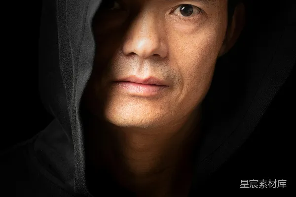 高清摄影 穿着深色连帽衫的男人，脸上有阴影。