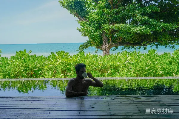 高清摄影 一个男人坐在木制地板上，旁边是一个池子。