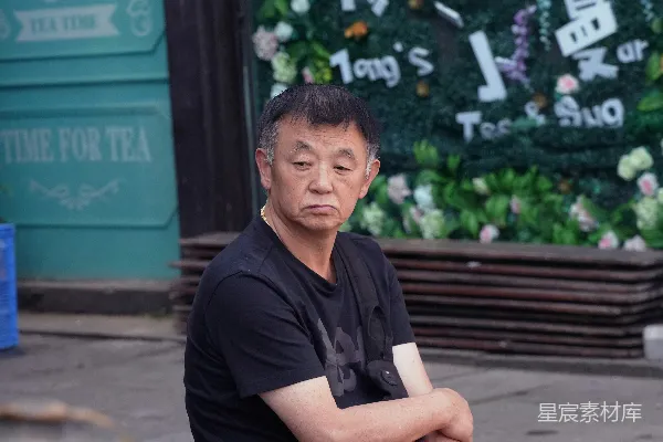 高清摄影 穿着黑色Polo衫的男子坐在棕色木制长凳上，时间是白天。
