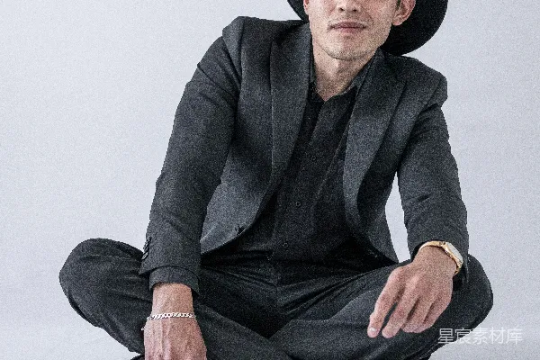 高清摄影 穿黑色西装和黑色裤子，戴着黑色帽子的男人坐在地上。
