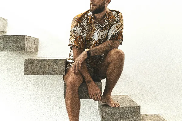 高清摄影 穿着棕色和白色条纹衬衫的男人坐在灰色混凝土长椅上。