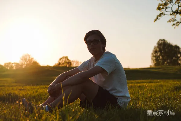 高清摄影 男人坐在草地上，夕阳西下。