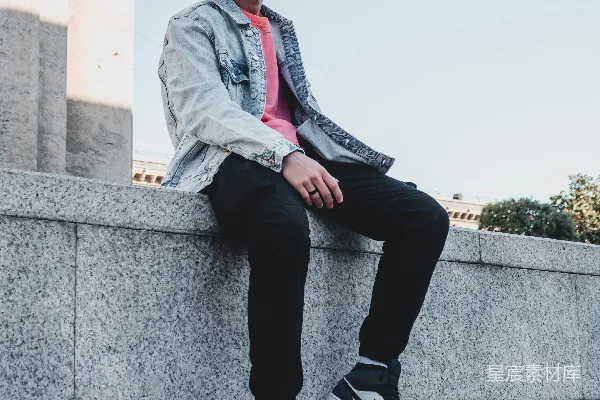 高清摄影 穿着灰色西装的男人坐在白天的灰色混凝土墙上。