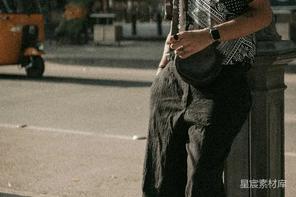 高清摄影 一个男人坐在一根杆子上，看着他的手机。