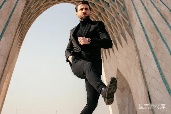 高清摄影 一个穿着黑色西装的男人在一座建筑物前摆姿势拍照。