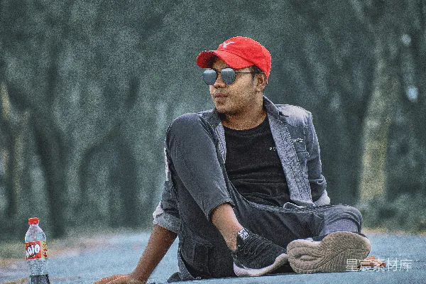 高清摄影 一个男人坐在地上，旁边放着一个瓶子。