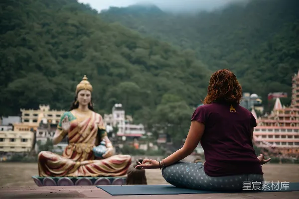 高清摄影 一位女士坐在瑜伽垫上，面前有一尊佛像。
