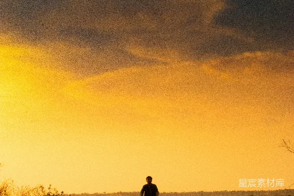 高清摄影 一对男女坐在棕色岩石上，夕阳西下。