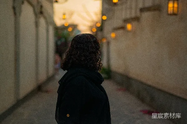 高清摄影 一位女性正在一栋建筑物旁的街道上行走。
