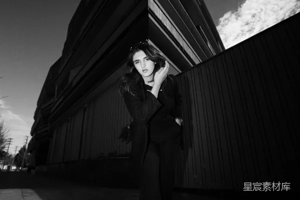 高清摄影 一个女人站在建筑物前的人行道上。