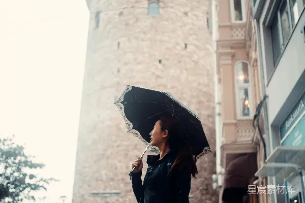 高清摄影 一个撑着雨伞的女人站在雨中。
