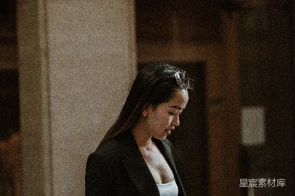 高清摄影 穿着黑色西装外套的女性站在白天的棕色混凝土建筑附近。