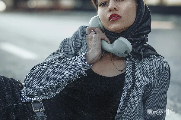 高清摄影 一个女人坐在路边打电话。
