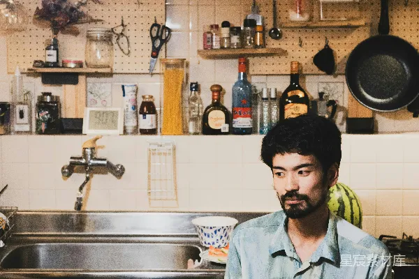 高清摄影 一个人坐在厨房餐桌旁，面前有食物。